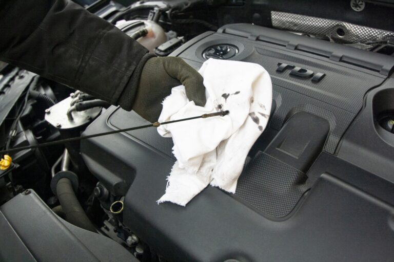 A person checks the oil and cleans the engine of a car, ensuring it runs smoothly and efficiently