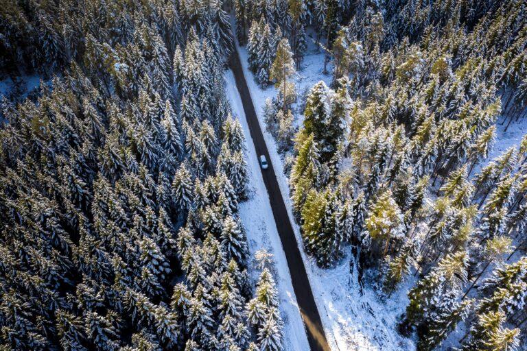 Aerial view of a winding road surrounded by a snowy winter forest
